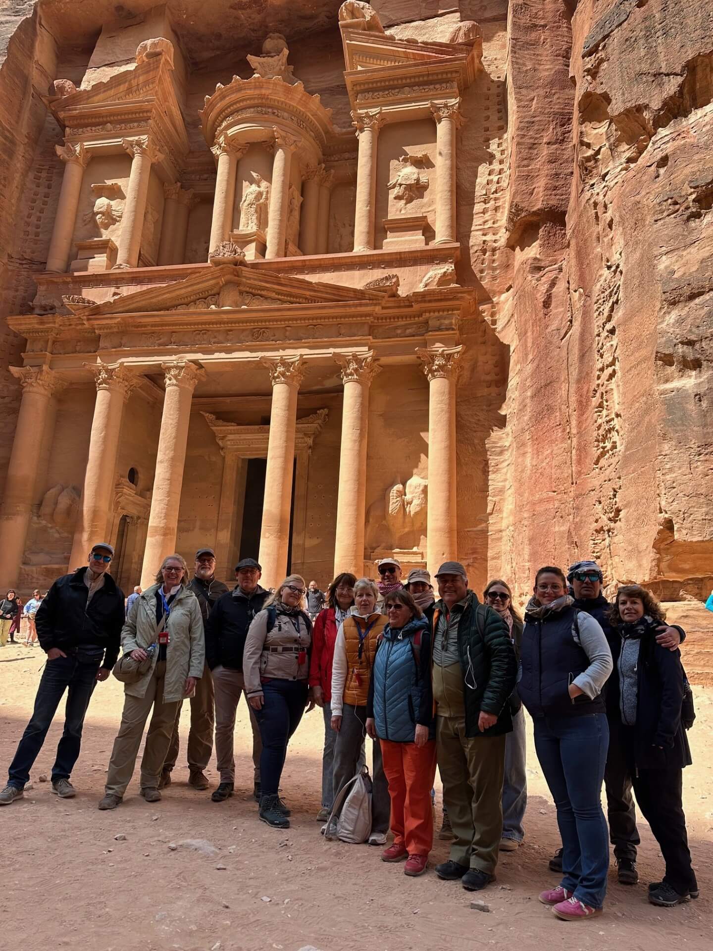 Eine Gruppe von Menschen vor der in den Felsen gehauenen Stadt Petra in Jordanien