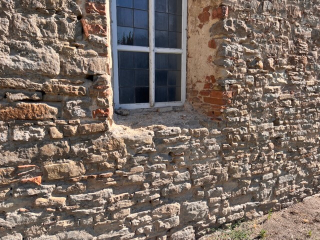 auf dem Bild ist ein Fenster in einer alten Mauer zu sehen