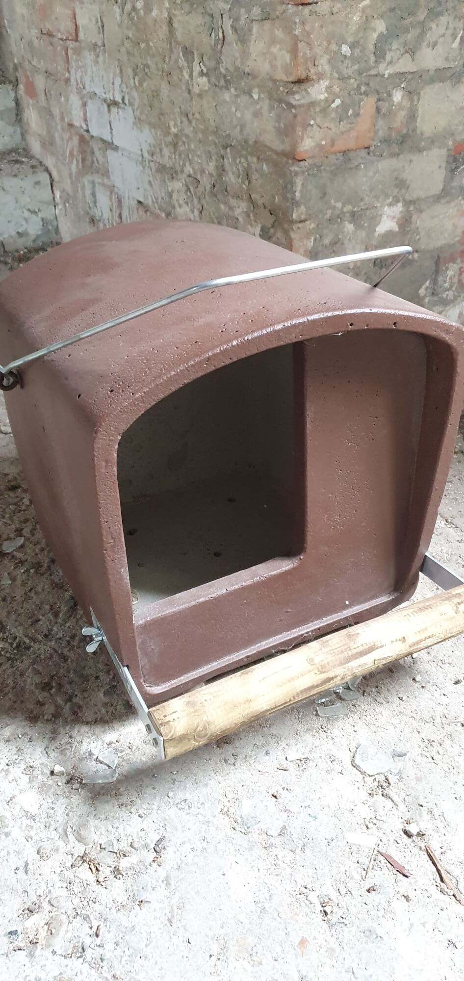 Auf dem Bild ist ein rötlicher Kasten mit einer großen Öffnung nach vorne zu sehen. Die Oberfläche des Kastens ist gewölbt.